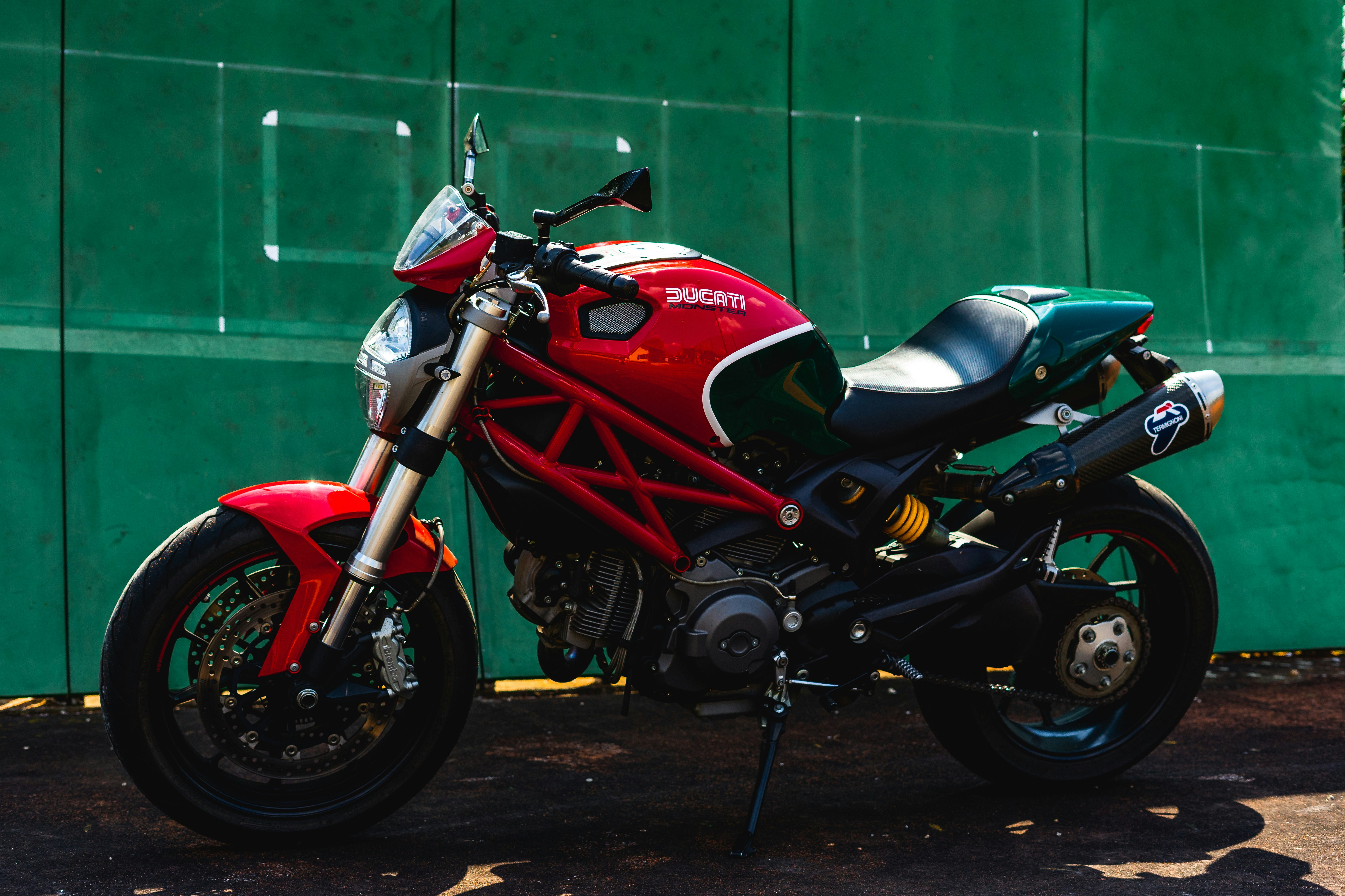 red and black sports bike parked beside green wall